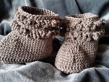 Gehäkelte graue Babyschuhe mit Rüschenbund und Knopf