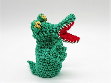 Grüne gehäkelte Krokodil-Fingerpuppe mit rotem Maul und gelben Augen