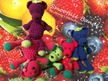 Fünf gehäkelte Amigurumi‑Teddys und Fruchtfiguren in Lila, Blau, Rot und Grün vor frischen Beeren und Orangen.