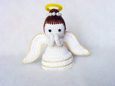 Gehäkeltes weißes Amigurumi-Engelchen mit Flügeln, goldfarbener Umrandung und gelbem Heiligenschein