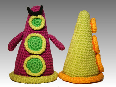 Two cone-shaped crocheted amigurumi: magenta with green circular appliqu
R
es and small arms, and lime-green with orange ruffles