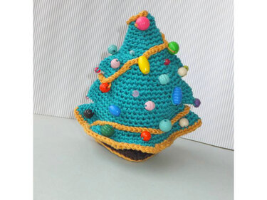 Türkiser gehäkelter Weihnachtsbaum mit gelber Zierkordel und bunten Perlen vor hellem Hintergrund