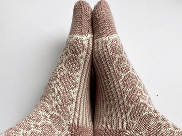 Paar gestrickter Damensocken in Rosé und Creme mit geometrischem Muster, Ansicht von oben