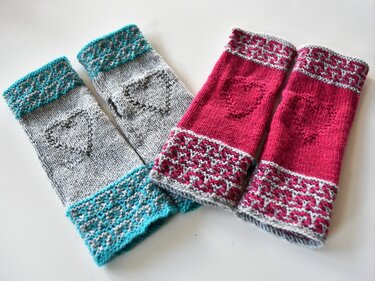 Zwei Paar gestrickte, fingerlose Armstulpen in Grau‑Türkis und Fuchsia mit Herzmotiven