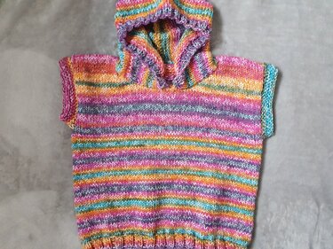 Bunter gestrickter Kinderponcho mit Kapuze und kurzen Ärmeln, flach liegend
