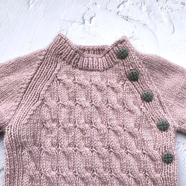 Rosa gestrickter Baby-Pullover mit Zopfmuster und Schulterknöpfe