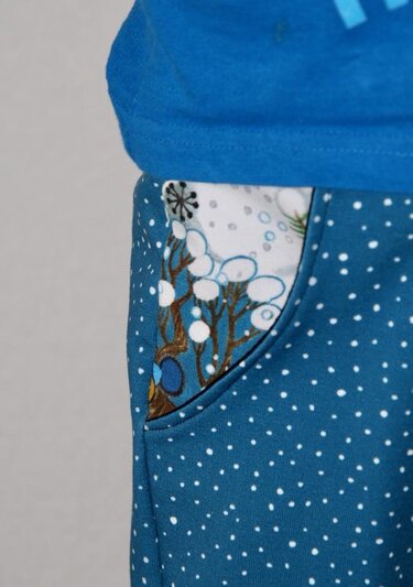 Detail einer blauen Kinderhose mit weißen Punkten und kontrastierendem Taschenfutter