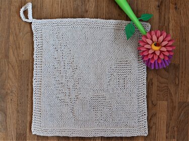 Hellbeiges gestricktes Spültuch mit Blatt- und Pilzmuster und Aufhängeschlaufe auf Holzfußboden