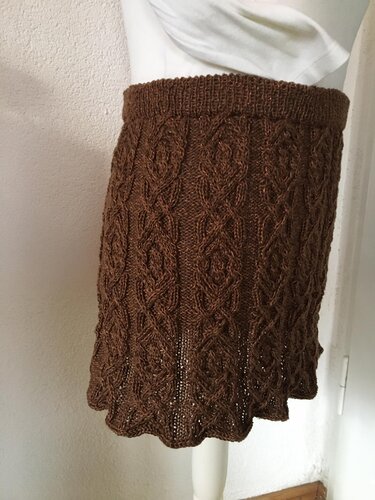 Brauner gestrickter Damenrock mit Zopfmuster auf Schaufensterpuppe, seitliche Ansicht