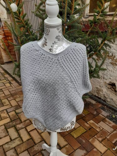 Mannequin mit hellgrauem gehäkelten Poncho, V-Ausschnitt und strukturierter Maschenoptik