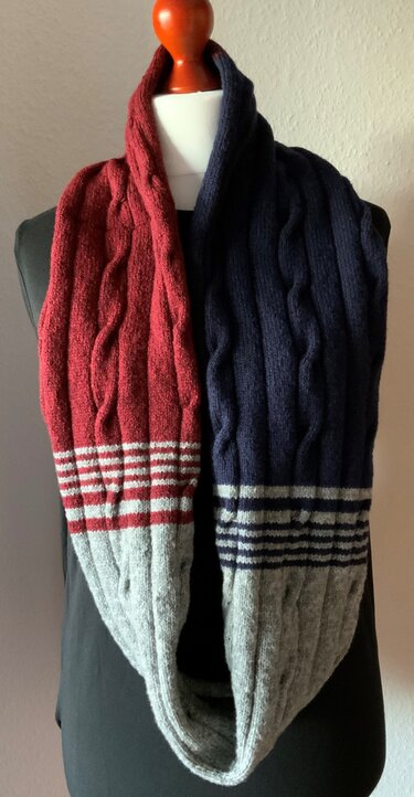 Gestrickter Loop‑Schal in Rot, Dunkelblau und Grau mit Zopfmuster auf einer Schaufensterpuppe