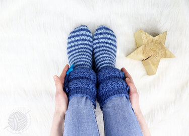 Top view of feet in blue striped crochet socks with folded textured cuffs and a button