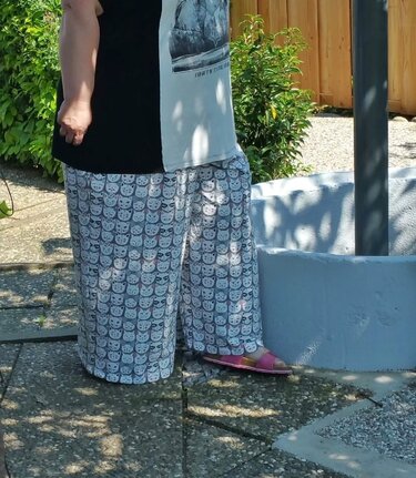 Weite knöchellange Damen-Culotte mit hellgrauem Katzenmuster und elastischem Bund, im Garten stehend