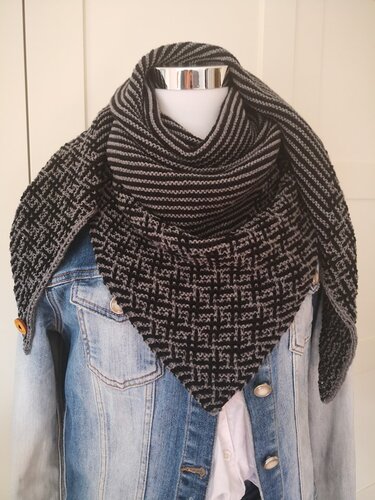 Schwarz-graues gestricktes Dreieckstuch mit Streifen- und Karomuster auf Schaufensterpuppe über Jeansjacke.