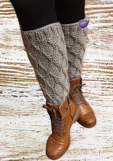 Kniehohe graue gestrickte Beinstulpen mit Zopfmuster über Leggings und braunen Schnürstiefeln