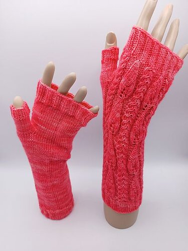 Korallfarbene gestrickte fingerlose Armstulpen mit Zopfmuster an Handmodellen