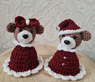 Zwei gehäkelte braune Teddybären in rot‑weißen Weihnachtsoutfits; links mit Schleife, rechts mit Zipfelmütze, als Eierwärmer.
