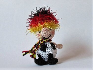 Häkel-Amigurumi mit Fußball, buntem Haar und Schal