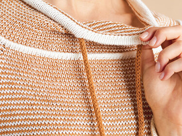 Detailaufnahme eines Strickmusters in Braun-Weiß mit Kordelzug und geripptem Bündchen