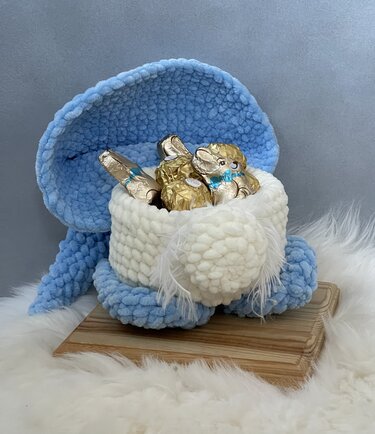 Gehäkelter blauer und weißer Wichtel mit abgenommener Haube, gefüllt mit Schokoladenfiguren