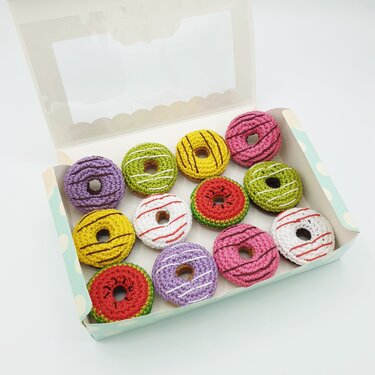 Bunte gehäkelte Mini‑Donuts in offener Geschenkbox