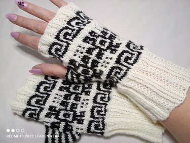 Weiße gestrickte fingerlose Armstulpen mit schwarzem geometrischem Muster an Händen