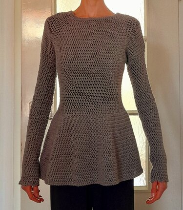 Gehäkeltes graues Langarm-Oberteil mit Rundhalsausschnitt und Peplum-Saum, frontal
