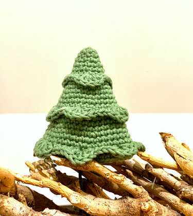 Kleiner gehäkelter Weihnachtsbaum auf Holzunterlage