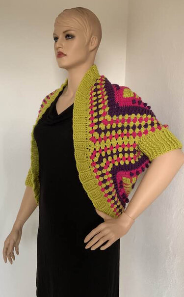 Gehäkelter Seelenwärmer in Limonengrün, Pink und Violett auf Mannequin, offene Front und kurze Ärmel