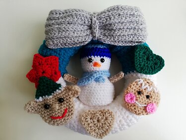 Bunter gehäkelter Türkranz mit Schneemann in der Mitte, Lebkuchen- und Elfengesicht, Herzen und großer silberner Schleife