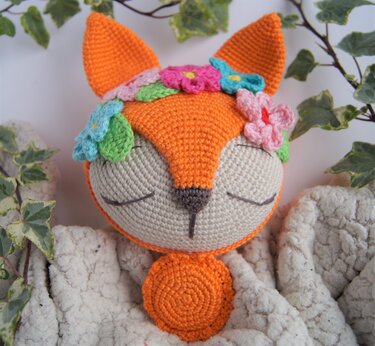 Gehäkelter orange-weißer Fuchs mit Blumenkranz und geschlossenen Augen
