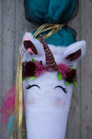 Detailaufnahme einer Einhorn-Schultüte mit Horn, Blumen, Ohren und türkisem Stoffabschluss