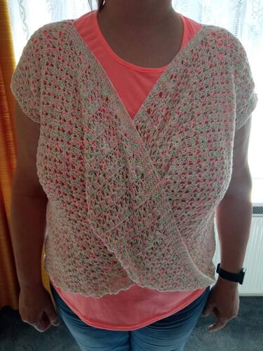 Gehäkeltes Wickelshirt in Pastellfarben über korallenfarbenem T‑Shirt.
