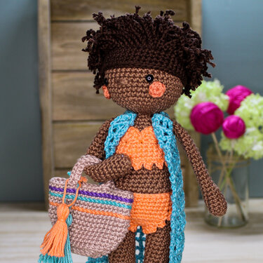 Gehäkelte Amigurumi-Puppe mit orangefarbenem Bikini, türkisfarbener Weste und gestreifter Tasche