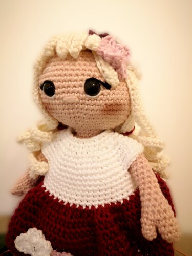 Gehäkelte Amigurumi-Puppe mit blonden Locken und weiß-rotem Kleid