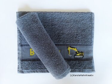 Graues Frotteehandtuch mit bestickter Zierborte: gelbes Baggermotiv und Initiale B im Kreuzstich.