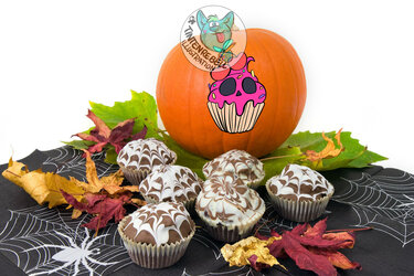 Pumpkin with skull-cupcake sticker beside marbled chocolate cupcakes on spiderweb napkins with scattered fall leaves