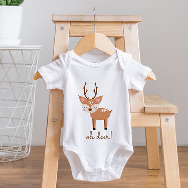 Weißer Baby-Body mit Rehkitz-Plot und dem Schriftzug „oh deer!“, an einem Holzkleiderbügel hängend.