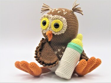 Gehäkelte braune Amigurumi-Eule mit gelber Augenpartie und Babyflasche