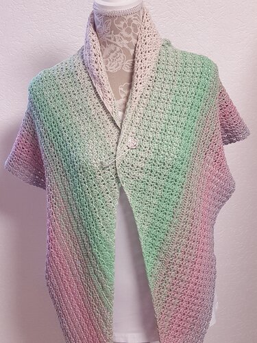 Gehäkeltes Dreieckstuch in Pastellfarben auf Schaufensterpuppe als Poncho mit Knopf