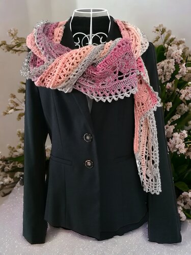 Crocheted shawl in pink, peach, and grey with openwork lace pattern and scalloped edge, displayed on a mannequin wearing a black blazer.