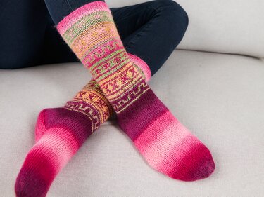 Nahaufnahme gestrickter Damensocken mit abgestuftem Farbverlauf und Ornamentstreifen