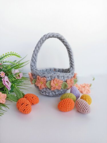 Gray crocheted basket with braided handle, peach flower trim, pastel crocheted eggs and small crocheted carrots