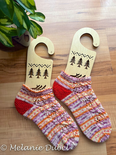 Paar kurze gestrickte Damensocken mit mehrfarbigen Streifen, Zierlochmuster und roter Ferse auf Holz‑Sockenspannern