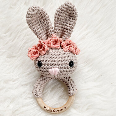 Gehäkelter Hasen-Greifring in Beige mit langen Ohren, rosa Blütenkranz und Holzring mit Schriftzug