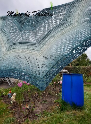 Gehäkeltes dreieckiges Tuch mit verlaufendem blau-grünem Garn und Spitzenrand an Wäscheleine