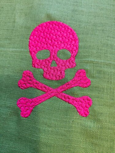 Gestickter pinker Totenkopf mit gekreuzten Knochen auf grünem Stoff