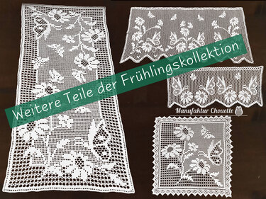 Vier weiße Filethäkel-Deckchen und ein Tischläufer mit Blumen- und Schmetterlingsmotiven auf dunklem Hintergrund.