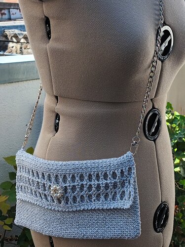 Hellblaue gehäkelte Clutch auf Schneiderpuppe mit Perlenverschluss und silberner Kette