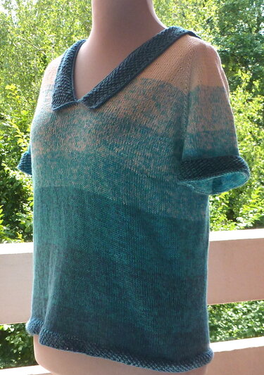 Gestricktes Damenshirt mit Farbverlauf von Cremeweiß zu Türkis, kurzen Ärmeln und V-Ausschnitt an einer Schaufensterpuppe